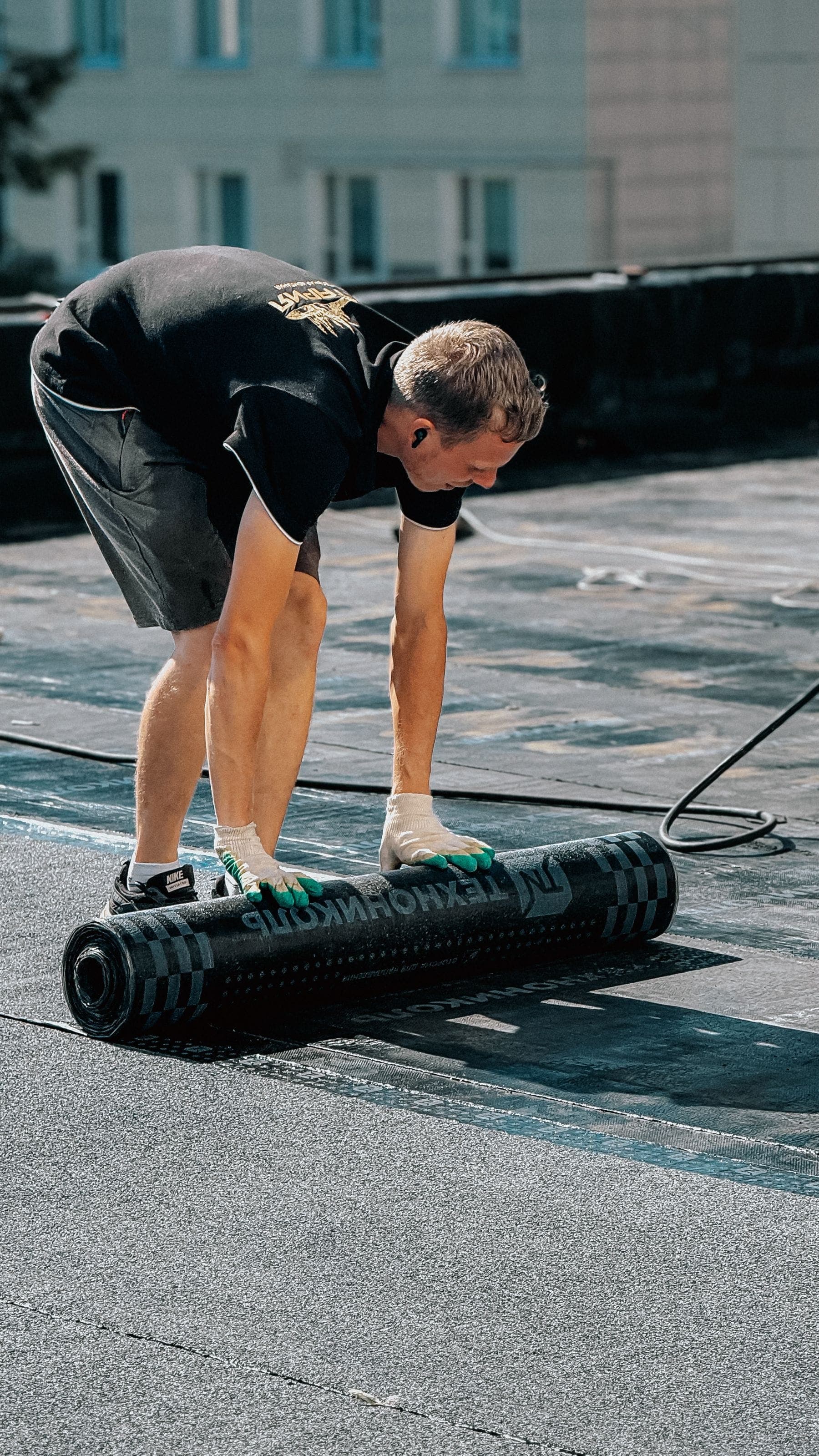 A roofer laying felt on a flat garage roof